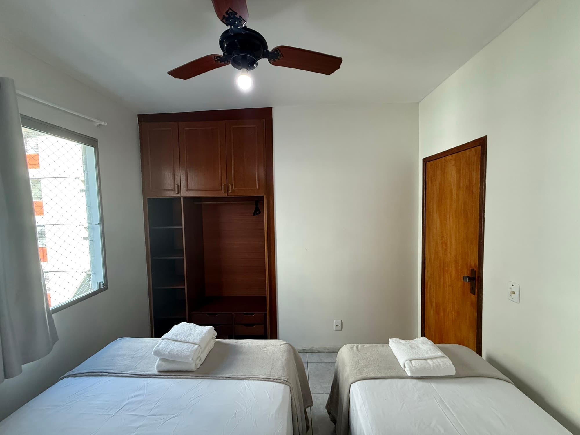 Quarto com duas camas de solteiro e guarda-roupa