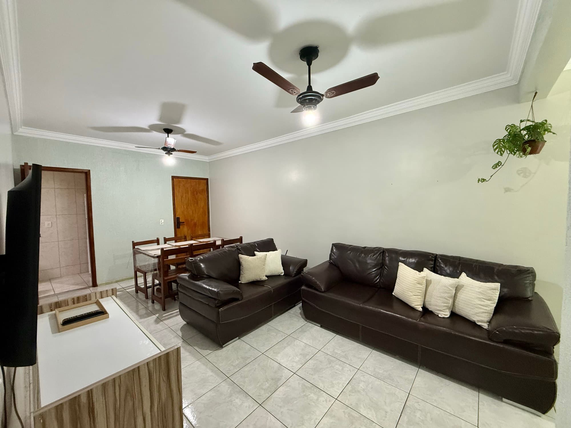 Sala de estar com sofás, mesa de jantar e varanda ao fundo