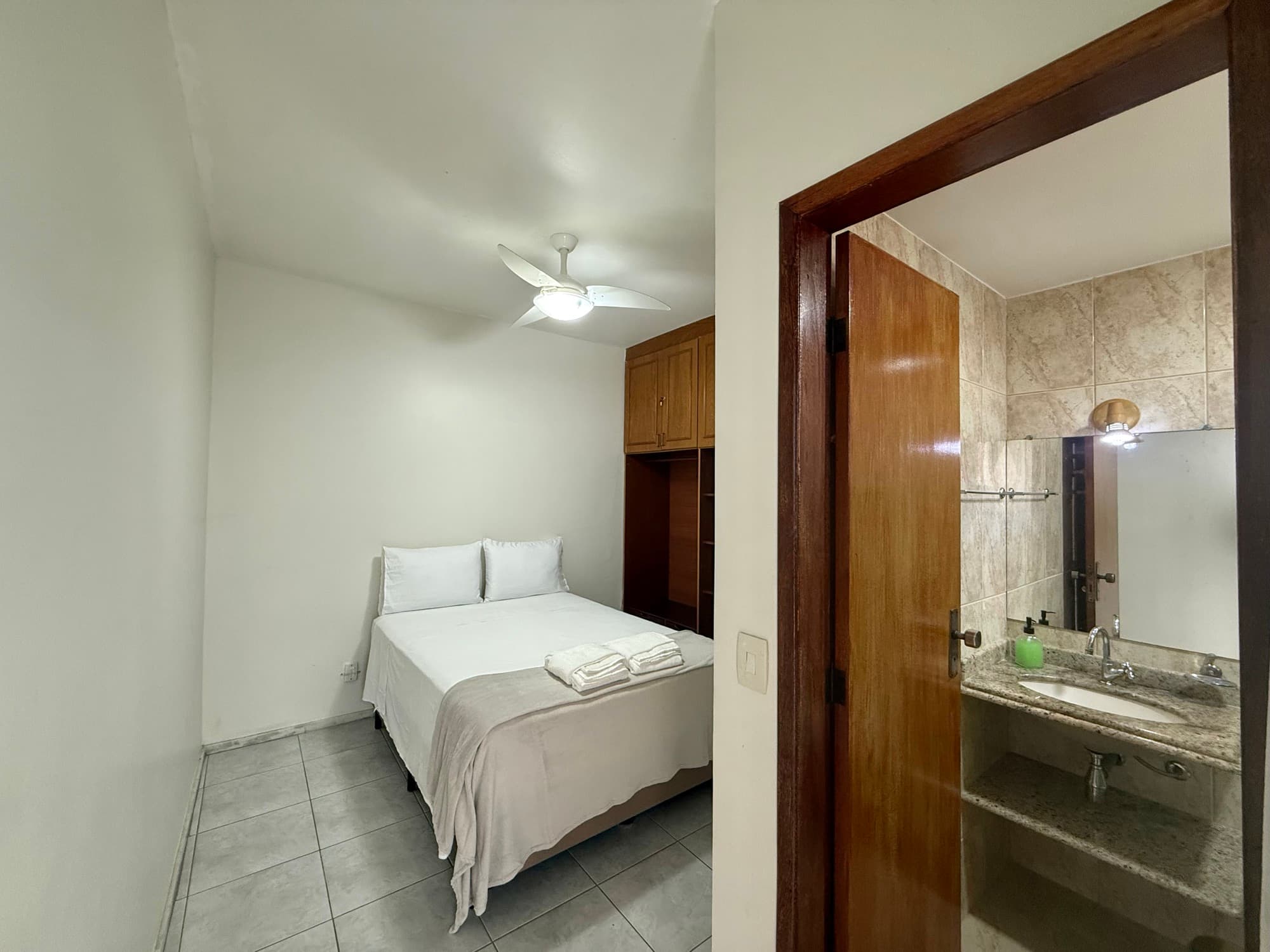 Suíte com cama de casal, guarda-roupa e banheiro próprio