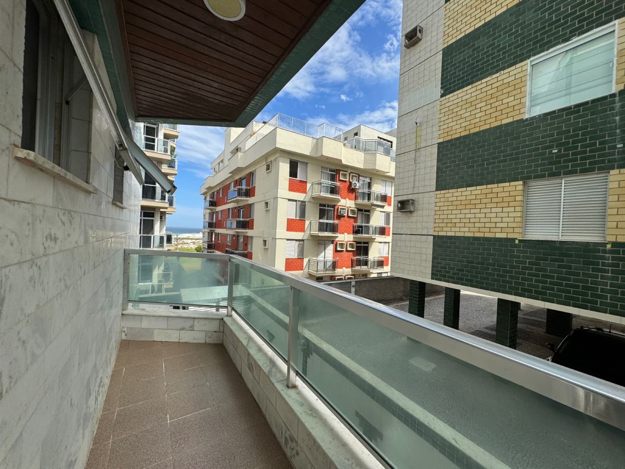 Varanda do apartamento com vista para o mar entre os prédios